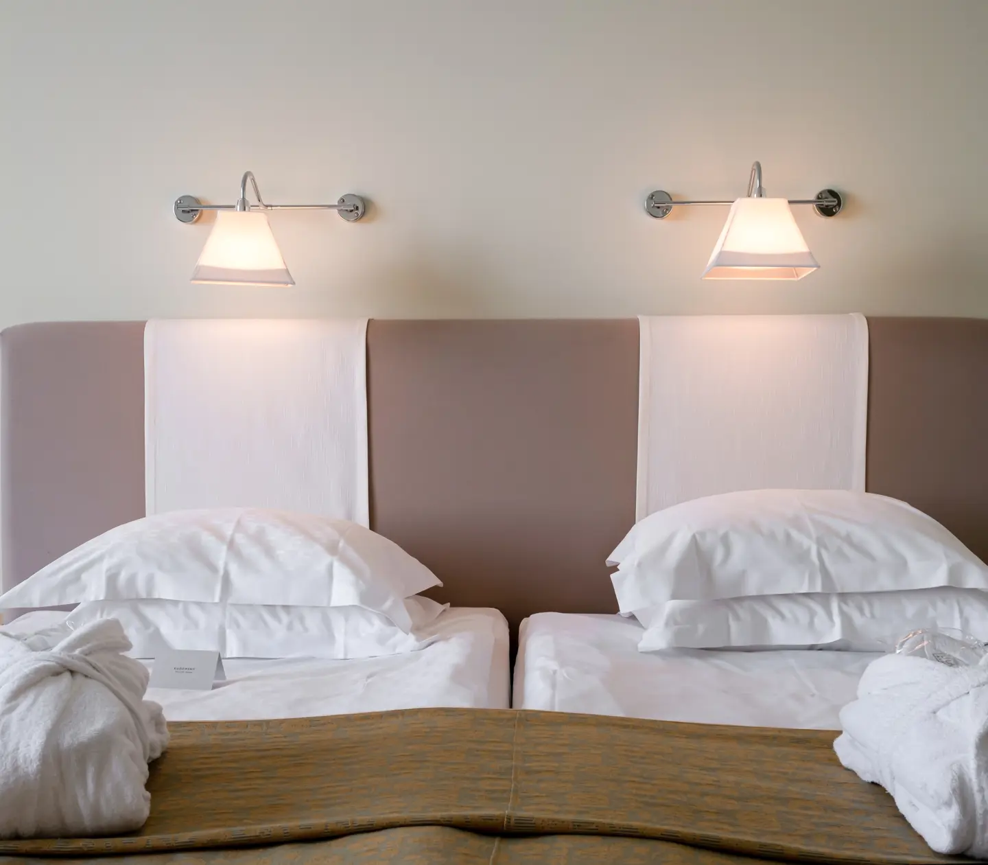 Hotellrum med säng, sänggavel och sänglampor