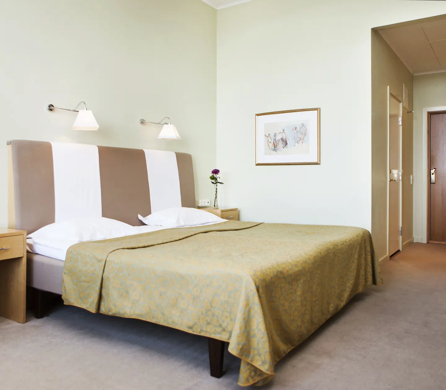 Hotellrum med säng, stor sänggavel och nattduksbord
