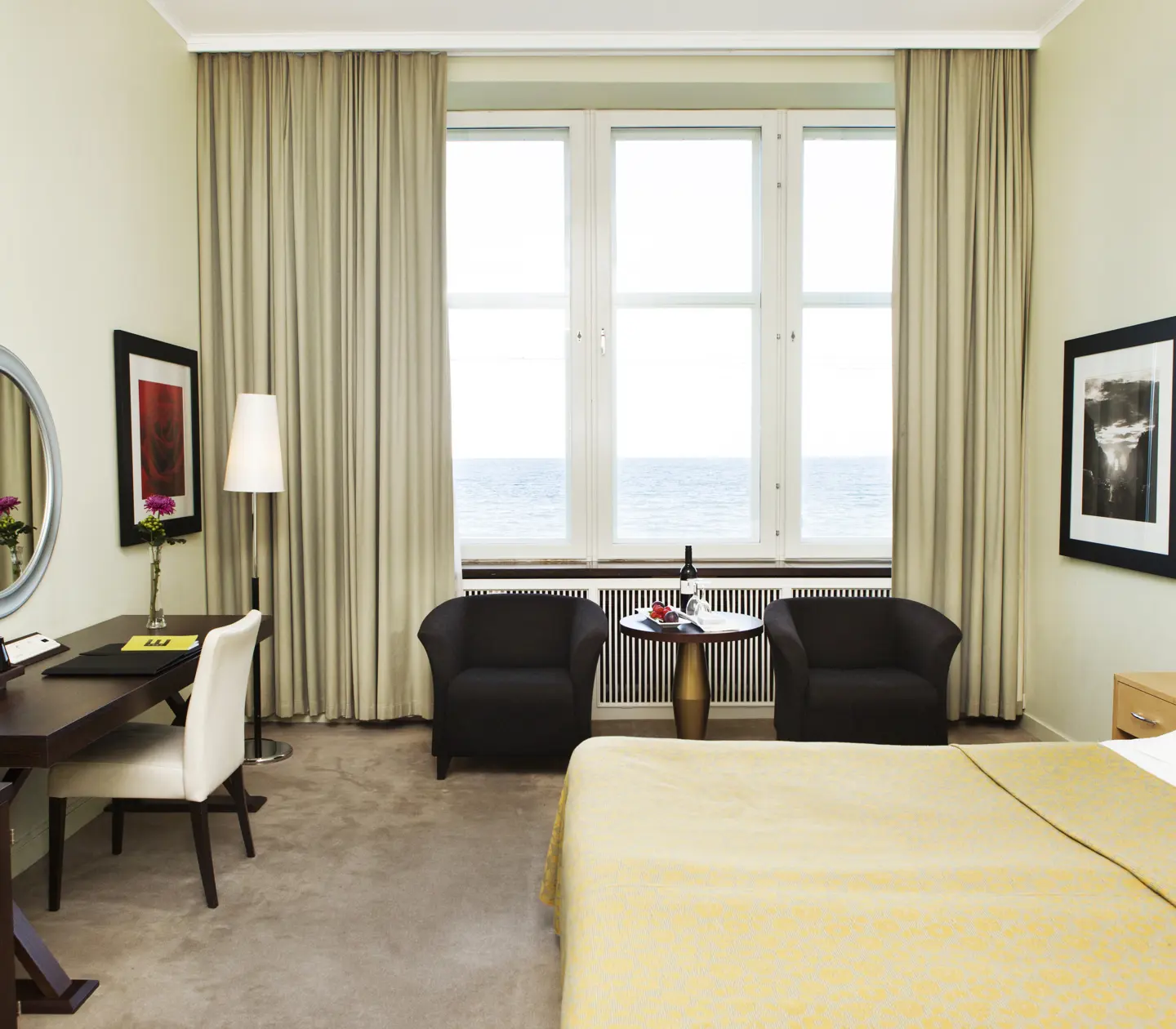 Hotellrum med säng, fåtöljer och havsutsikt