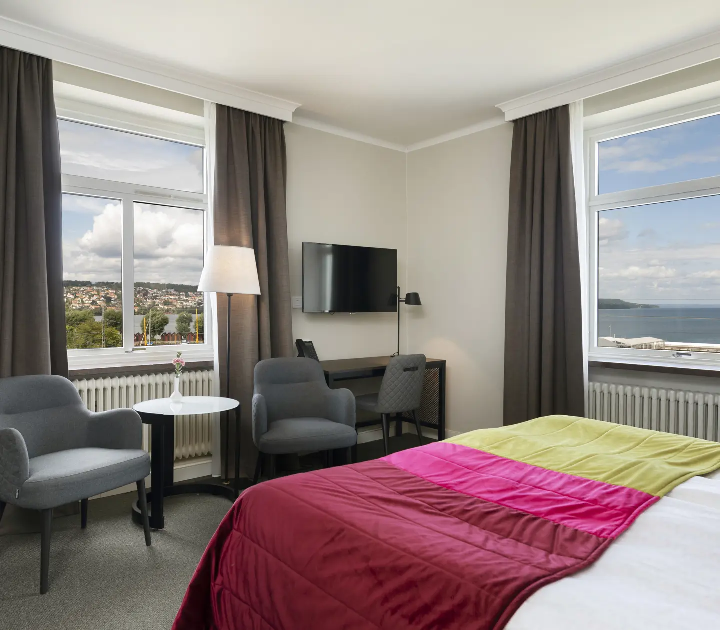 Hotellrum med säng, fåtöljer och havsutsikt