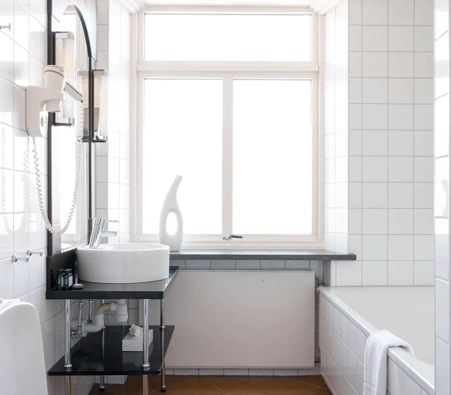 Ljust badrum med handfat, fönster och badkar