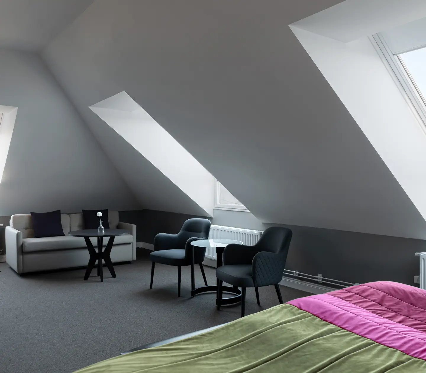 Hotellrum med fåtöljer, soffa och snedtak