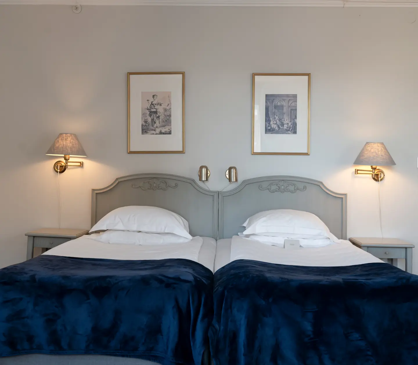 Hotellrum med säng, tavlor och sänglampor