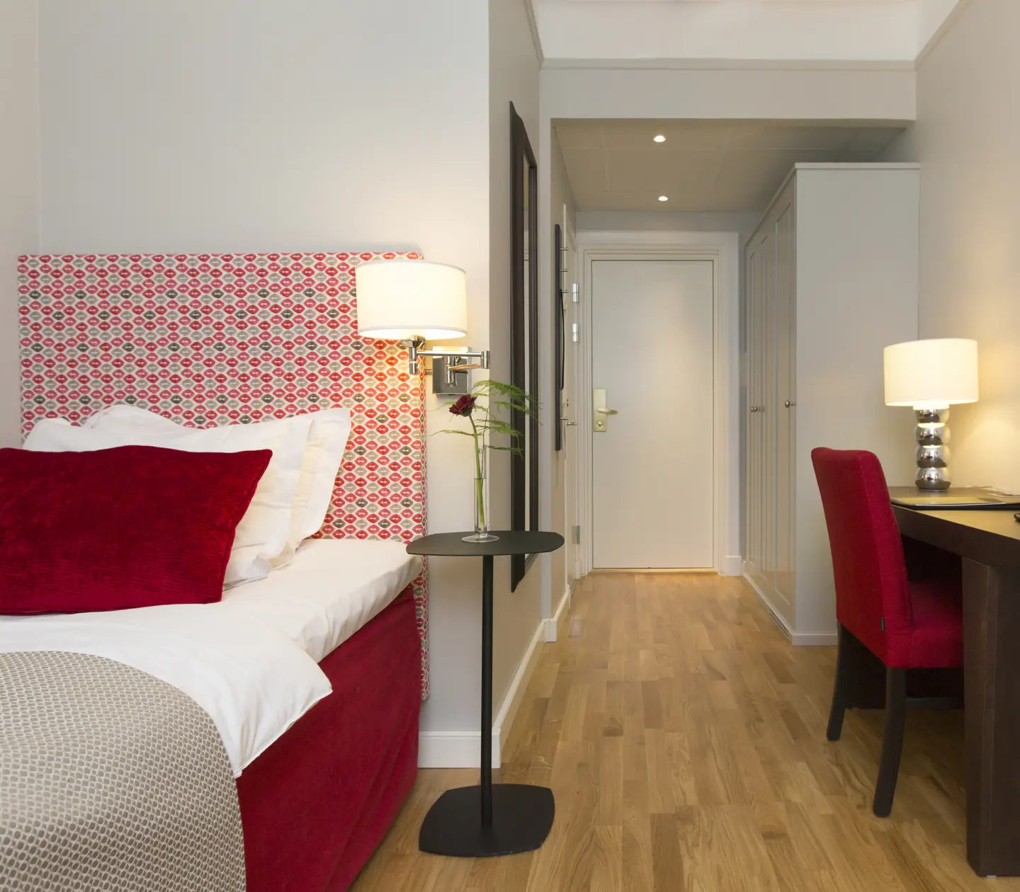 Hotellrum med enkelsäng, lampor och skrivbord