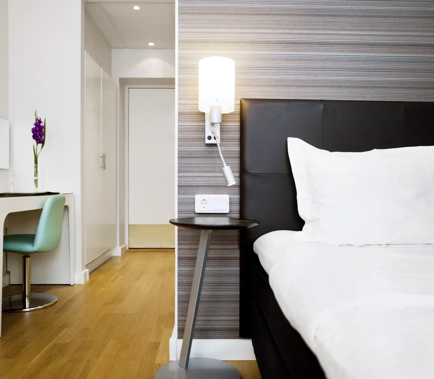 Hotellrum med enkelsäng, lampor och skrivbord