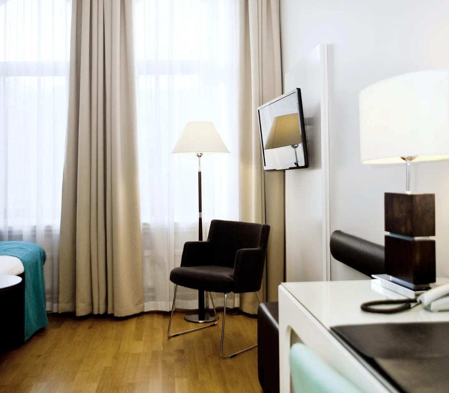 Hotellrum med fåtölj, golvlampa och tv