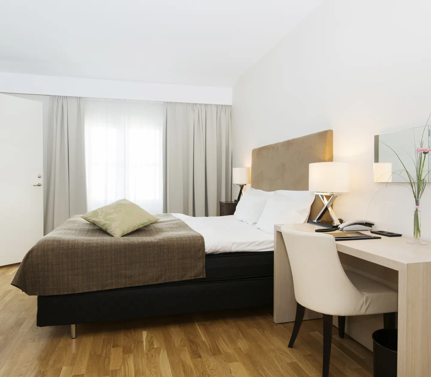 Hotellrum med dubbelsäng, skrivbord och fönster
