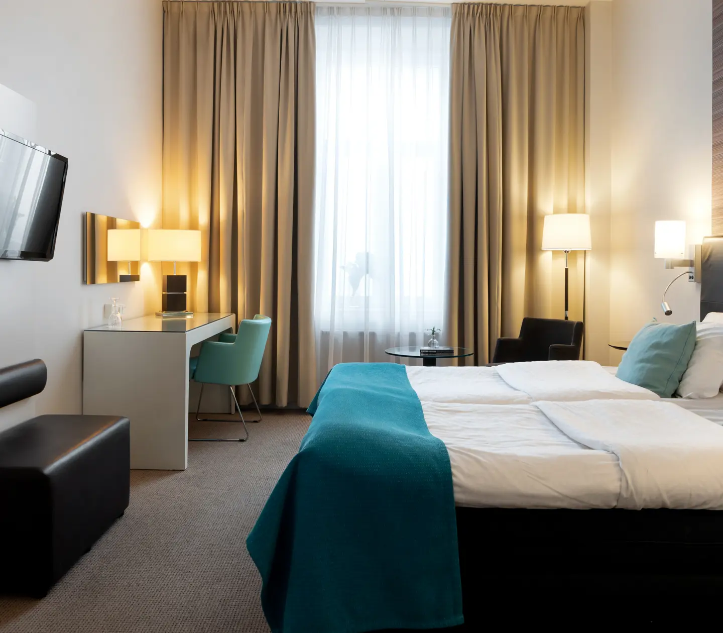 Hotellrum med dubbelsäng, skrivbord och tv