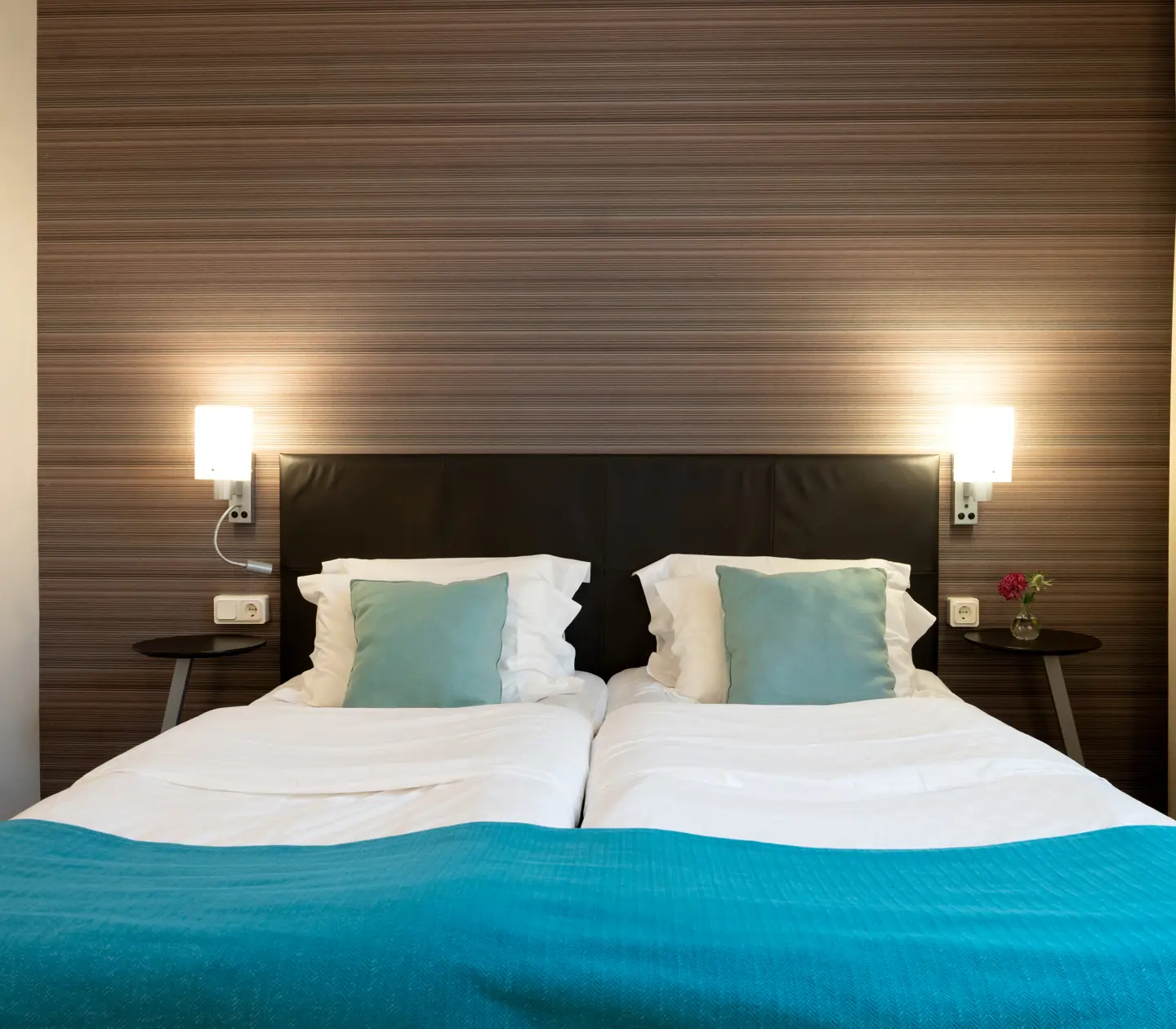 Hotellrum med dubbelsäng, tavla och sänglampor