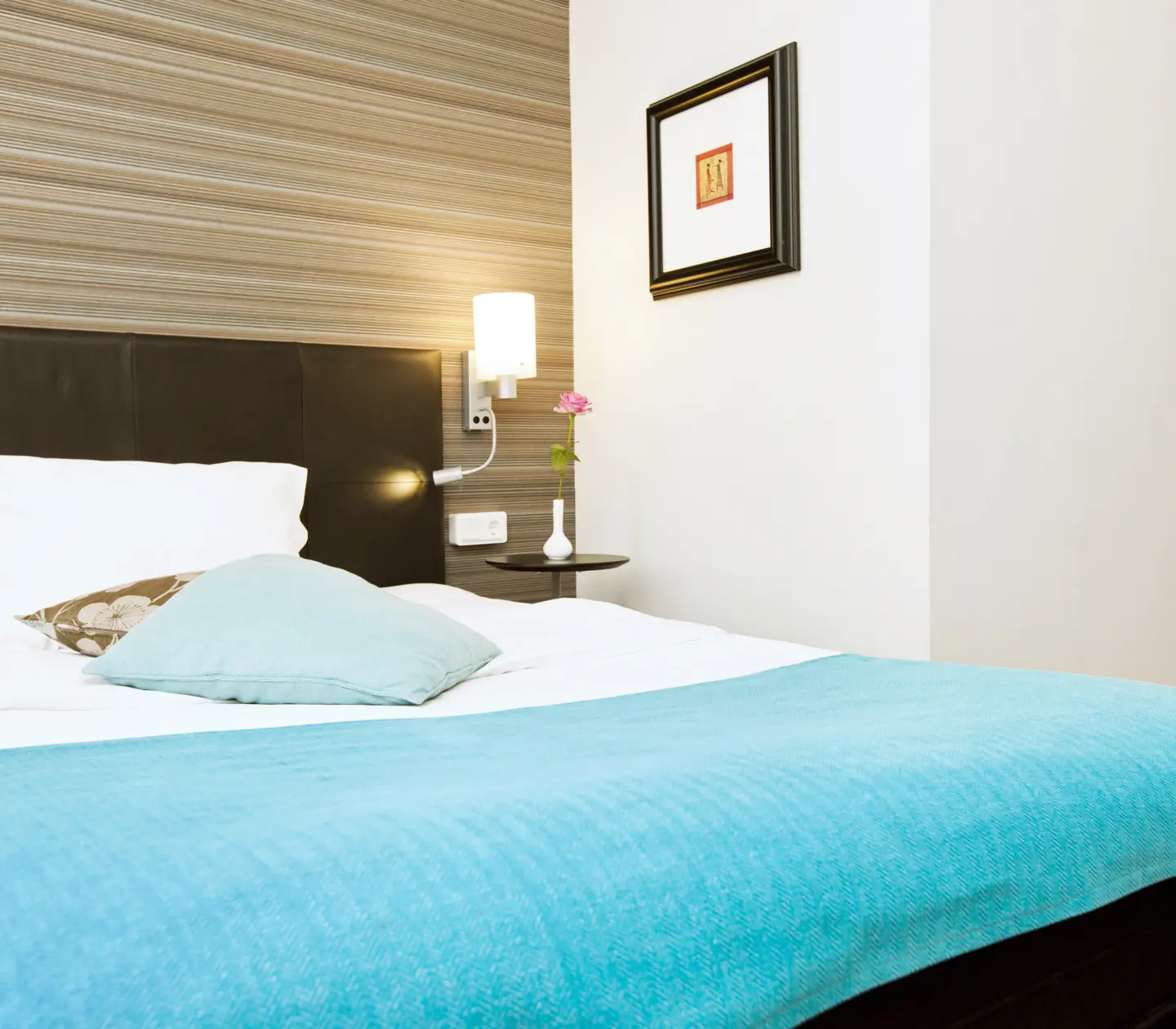 Hotellrum med dubbelsäng, tavla och sänglampa