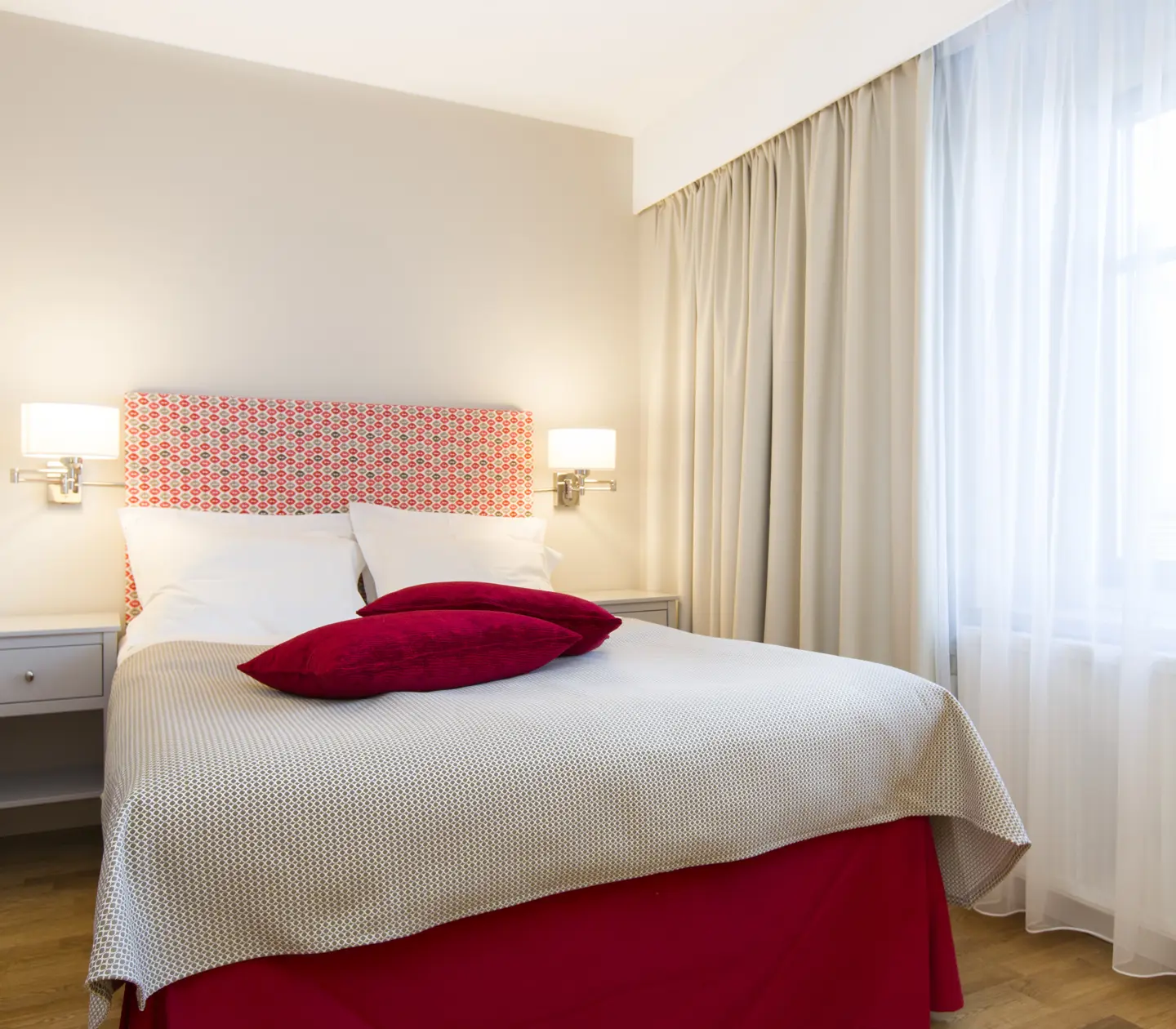 Hotellrum med dubbelsäng, sänglampor och fönster