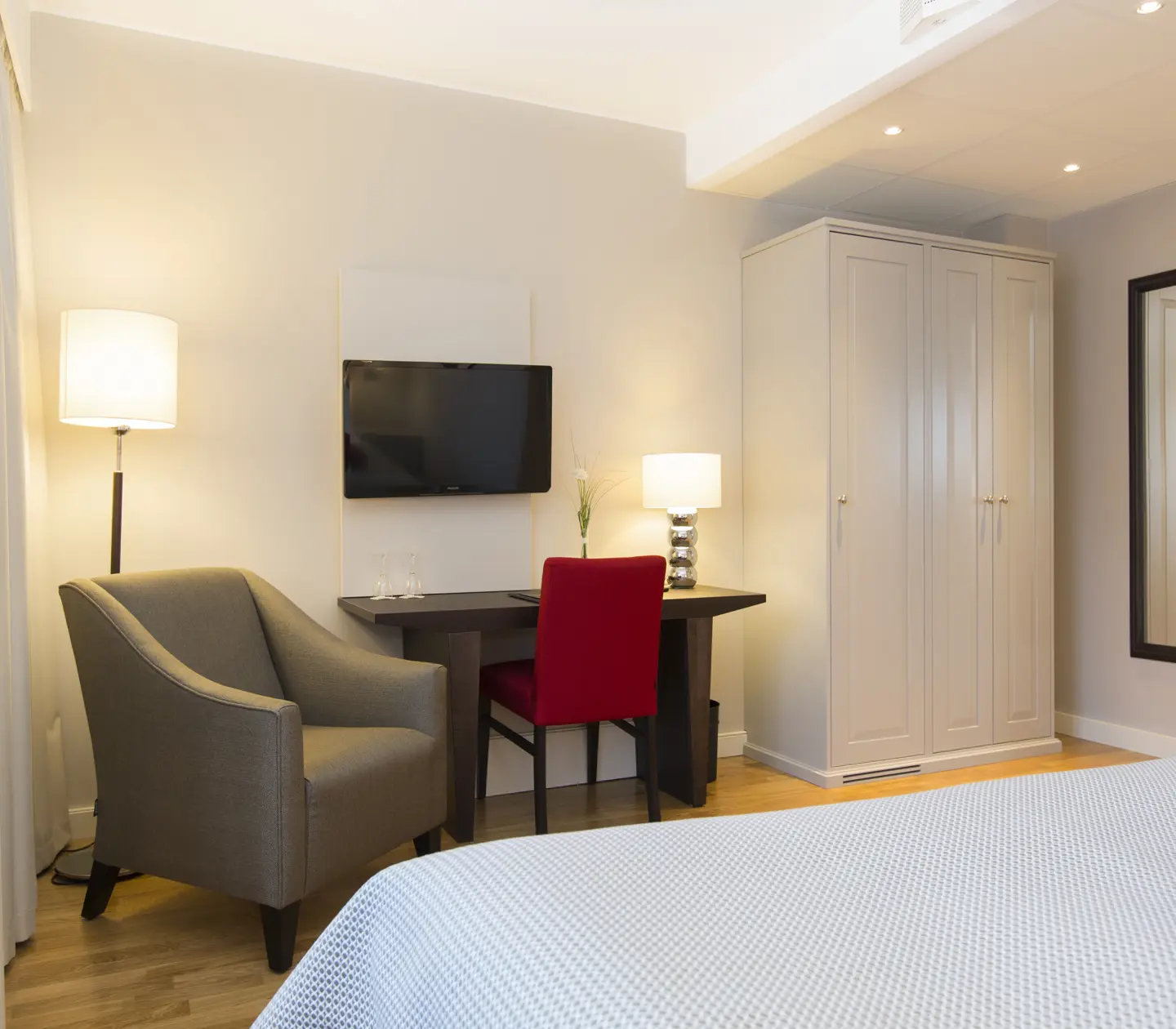 Hotellrum med garderob, skrivbord och fåtölj