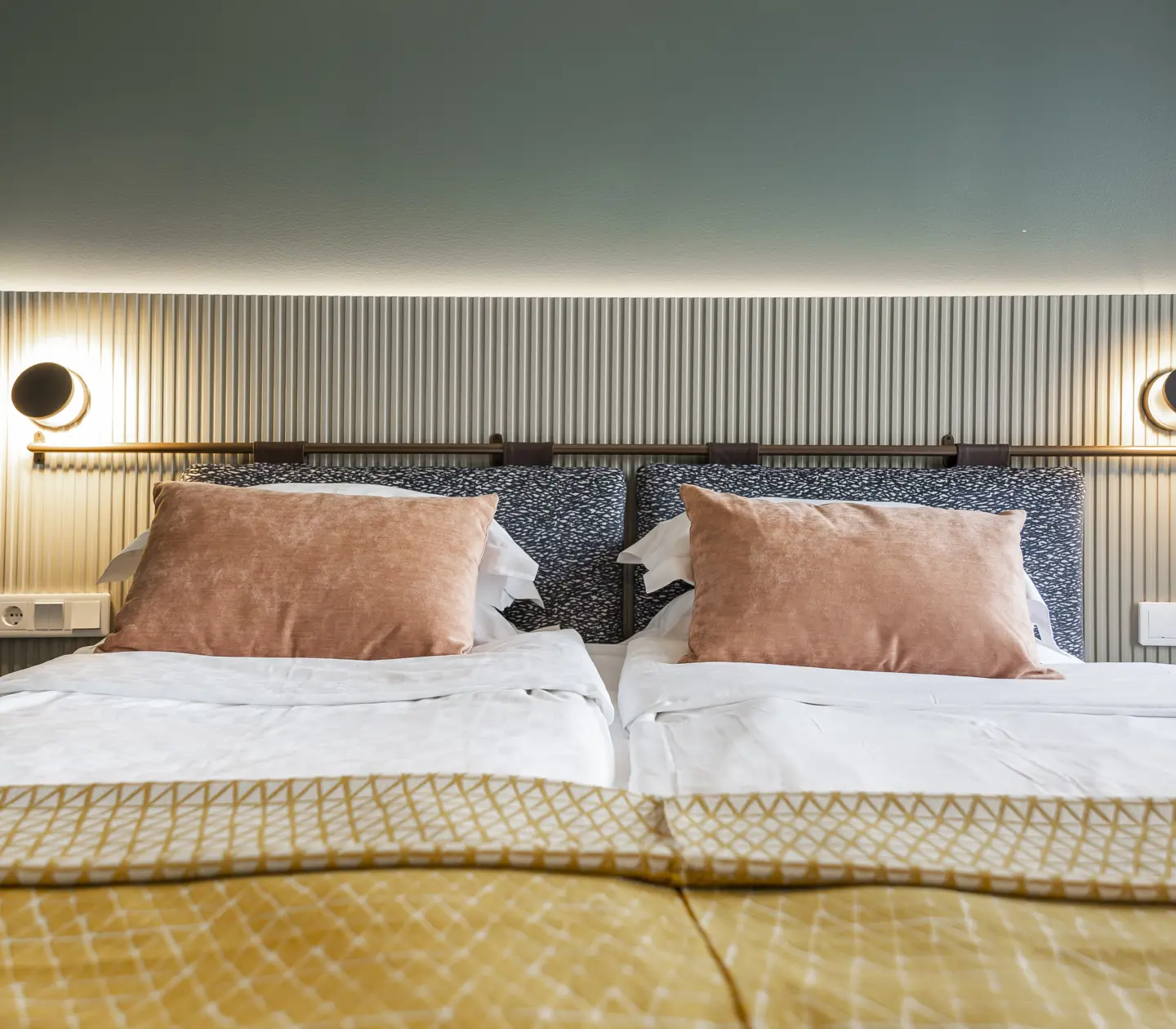 Ombonat hotellrum med dubbelsäng, varma textiler och sänglampor