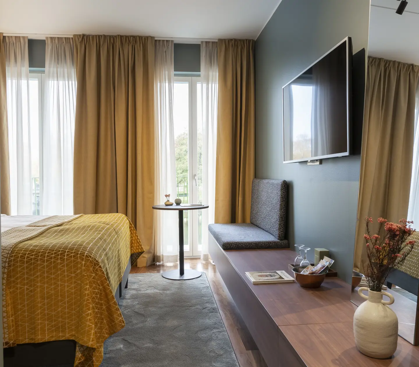 Ombonat hotellrum med tv, varma textiler och stora fönster
