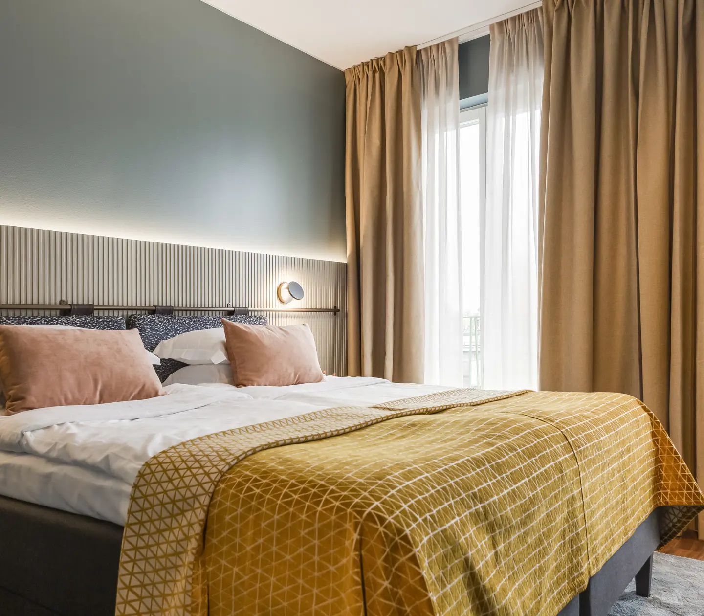Ombonat hotellrum med dubbelsäng, varma textiler och stora fönster