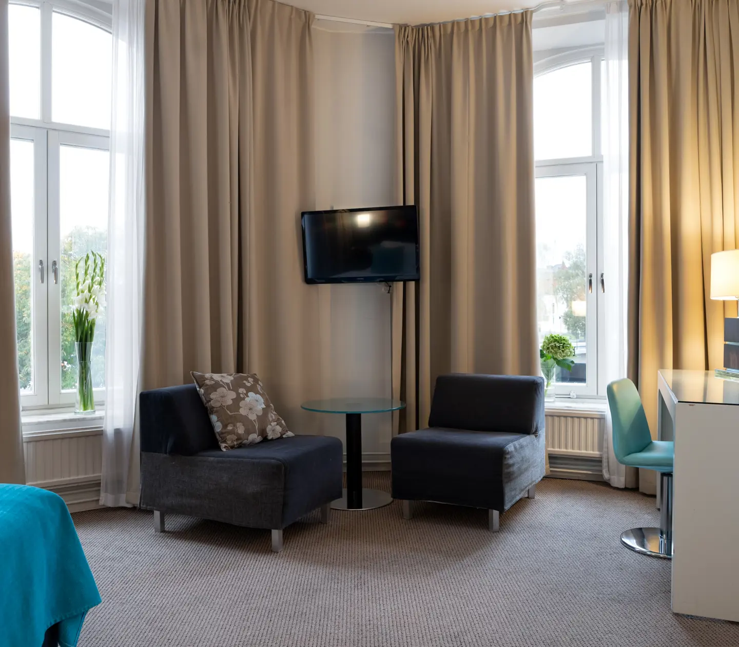 Ljust hotellrum med fåtöljer, skrivbord och stora fönster
