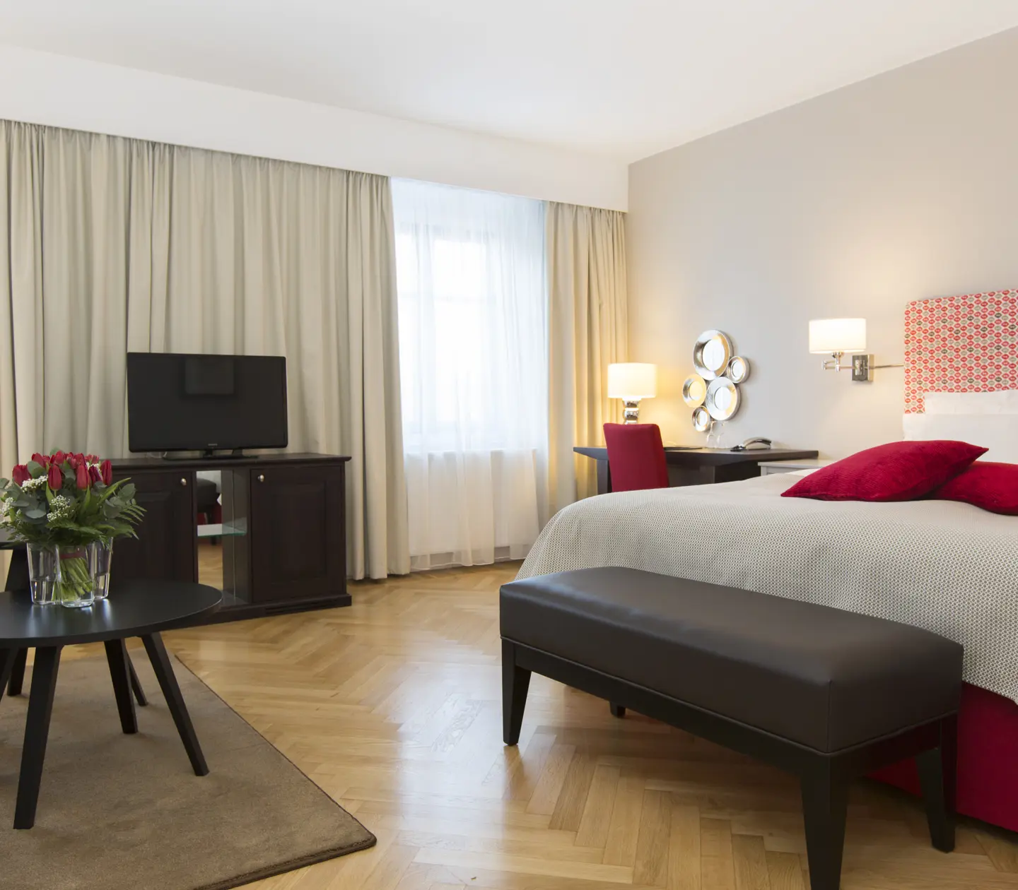 Ljust hotellrum med dubbelsäng, skrivbord och tv