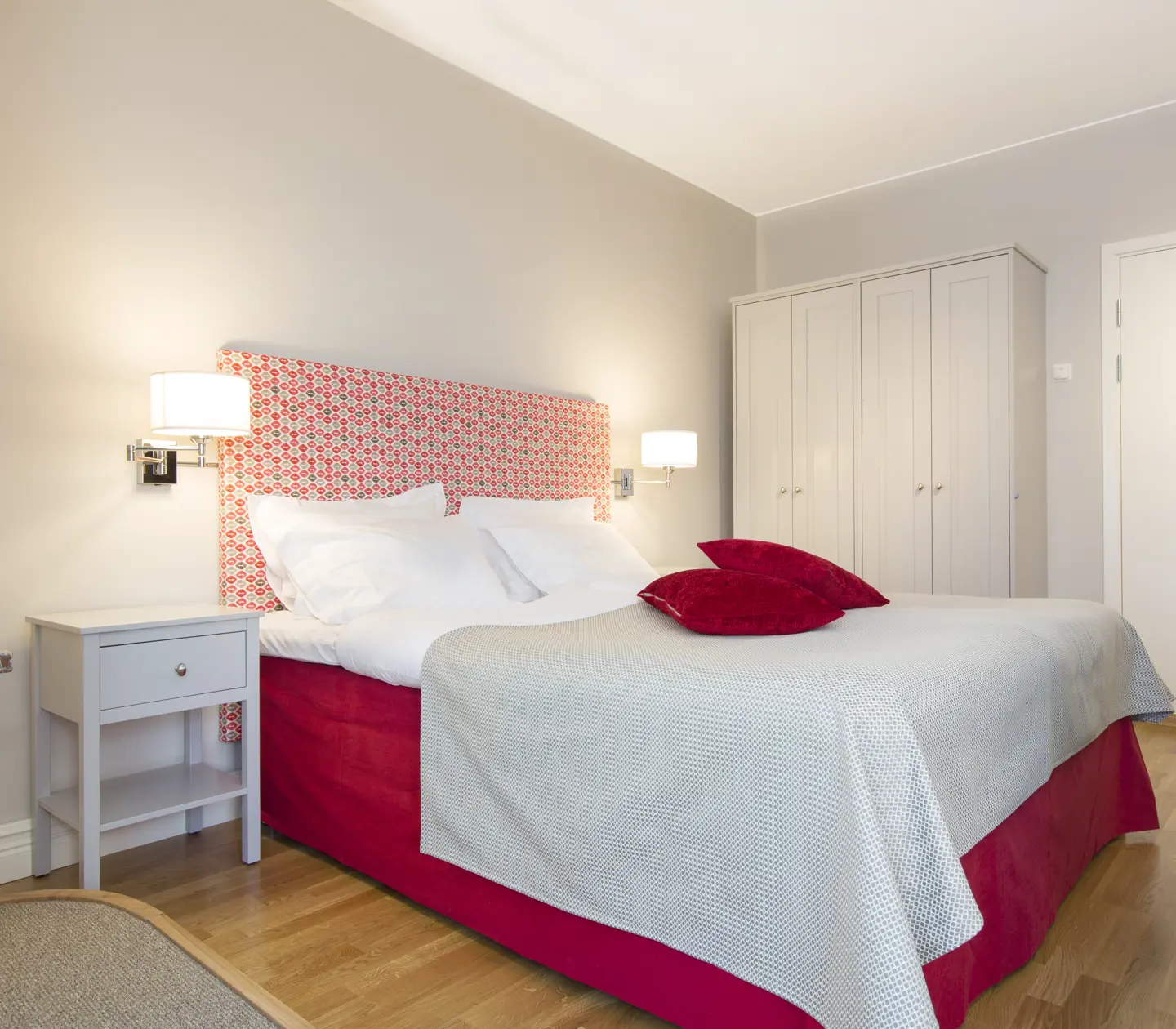 Ljus svit med säng, garderob och sänglampor