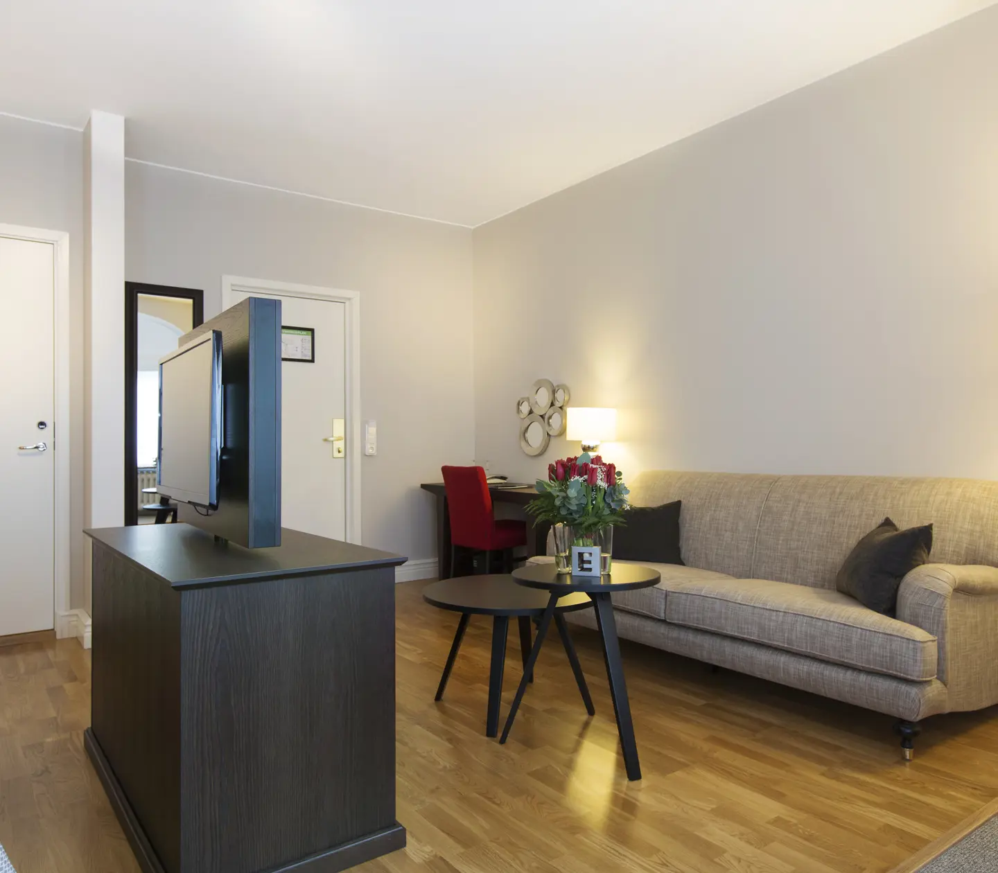 Ljus svit med soffa, skrivbord och rosbukett
