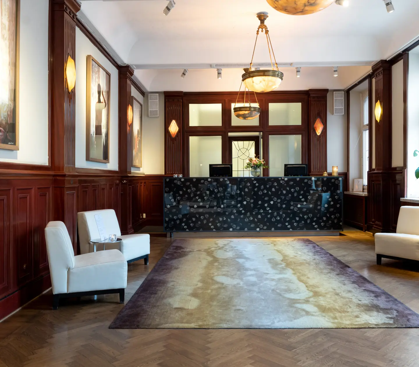 Hotellobby med receptionsdisk, fåtöljer och tavlor