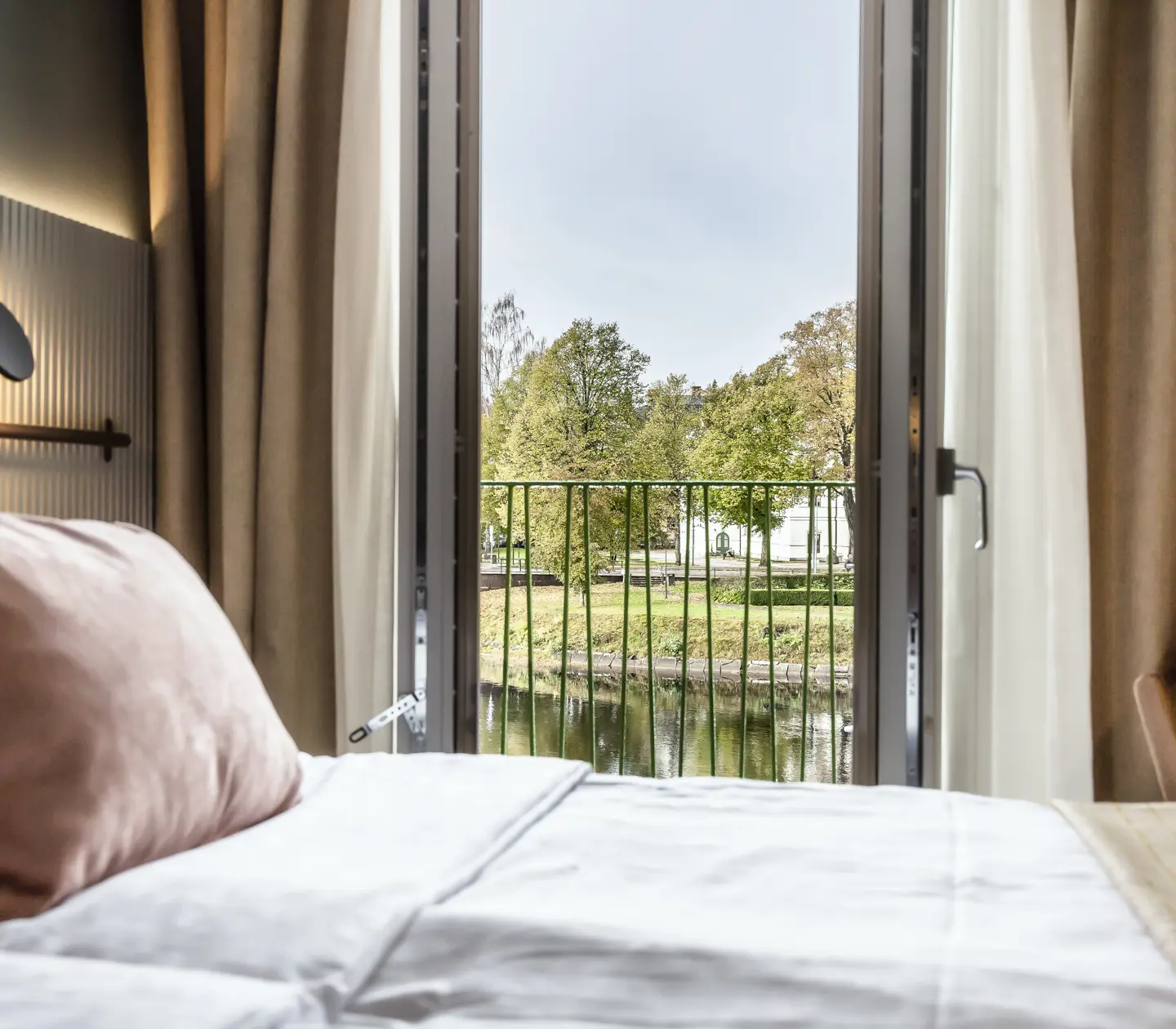 Hotellrum med säng och öppen balkongdörr med utsikt över Klarälven