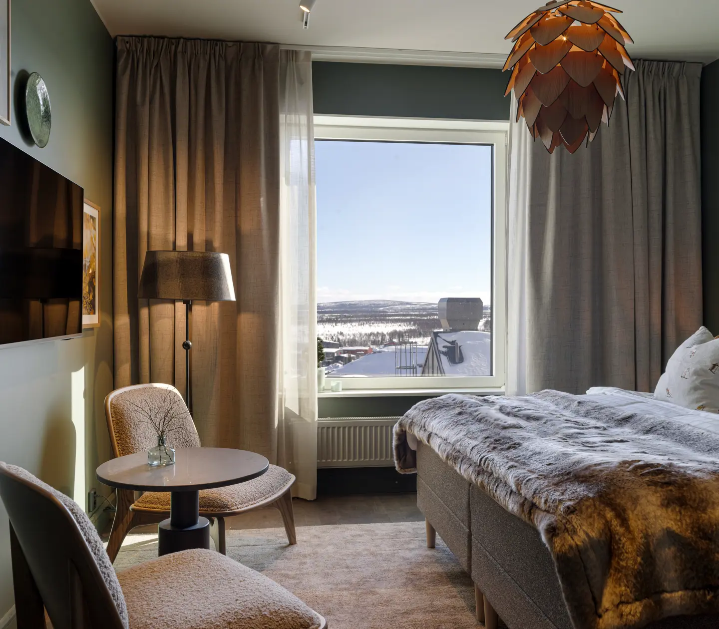 Mysigt hotellrum med säng, taklampa, fönster och fåtöljer