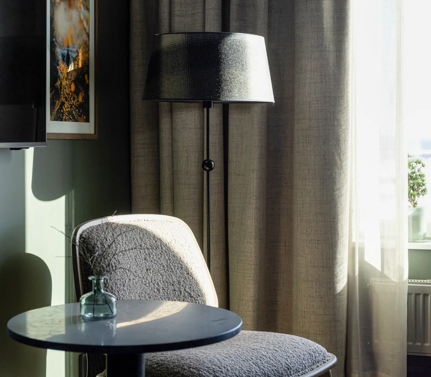 Mysigt hotellrum med fåtölj, golvlampa och gardiner