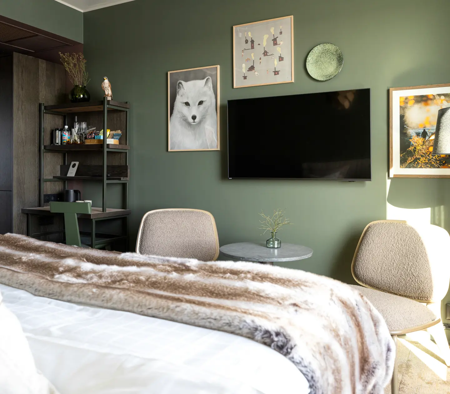 Mysigt hotellrum med tavlor, tv, fåtöljer och skrivbord