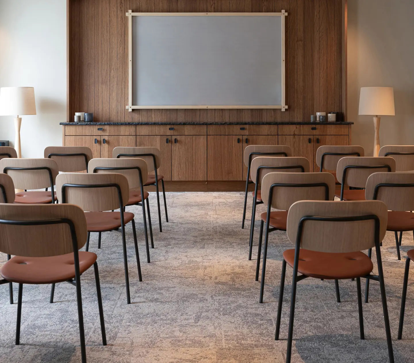 Mysig konferenslobby på kvällen med modern inredning, eleganta möbler och stämningsfull belysning, med utsikt över en naturnära omgivning genom stora fönster.