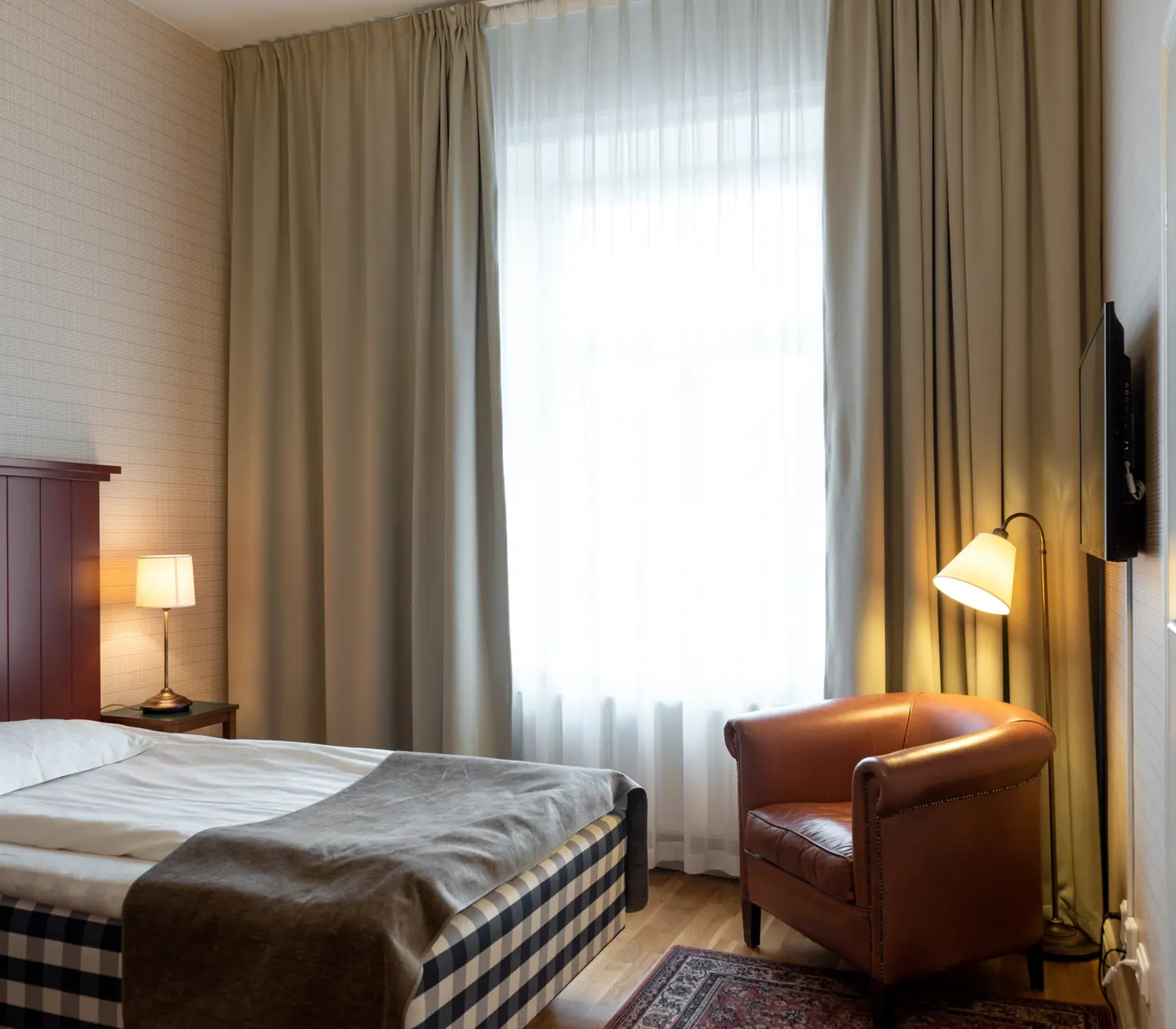 Hotellrum med Hästens-säng, läderfåtölj och fönster