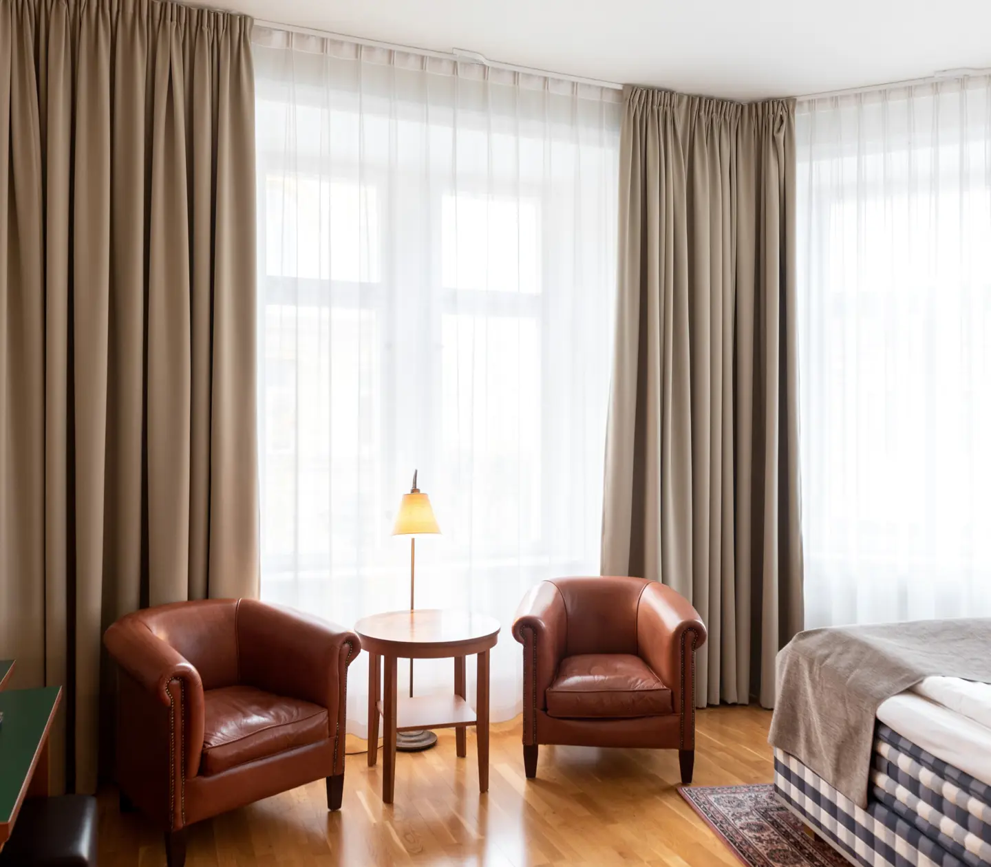 Hotellrum med Hästens-säng, läderfåtöljer och fönster