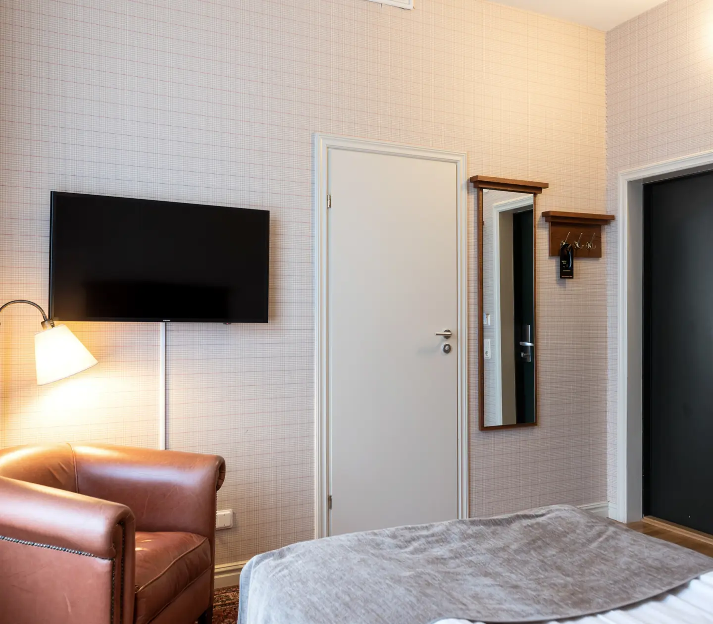 Hotellrum med tv, läderfåtölj och spegel