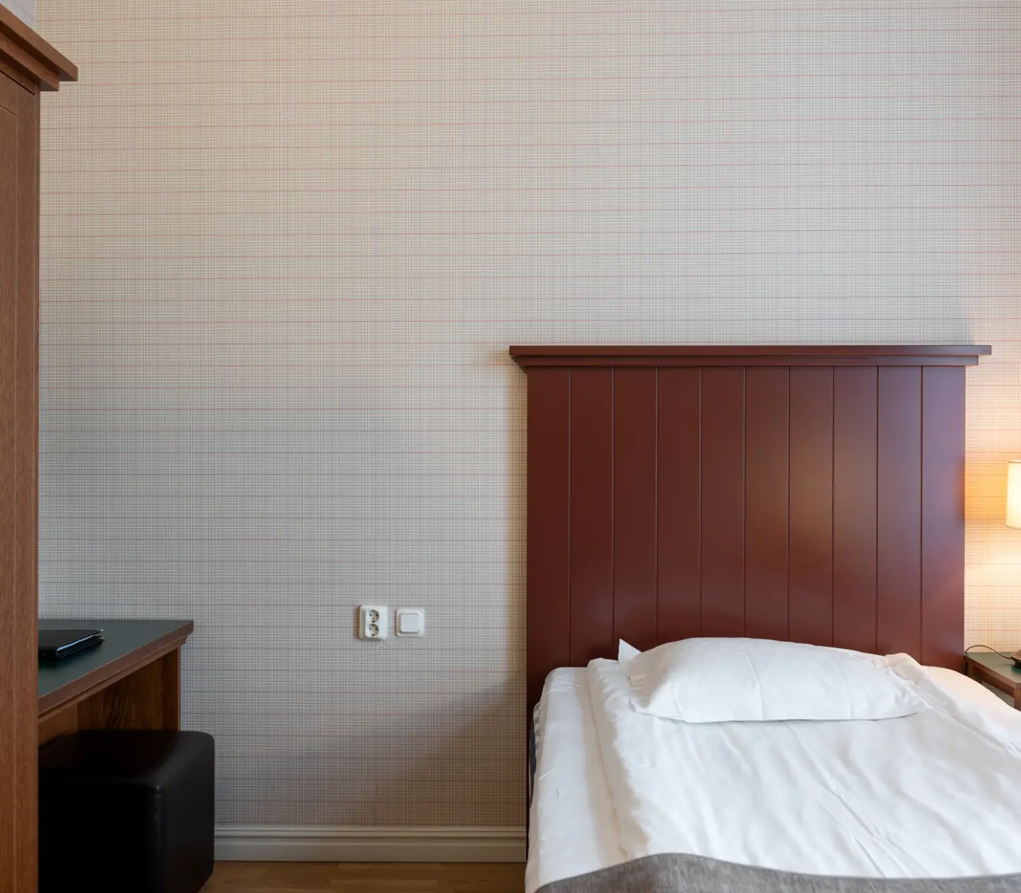 Hotellrum med säng, sänggavel i trä och garderob