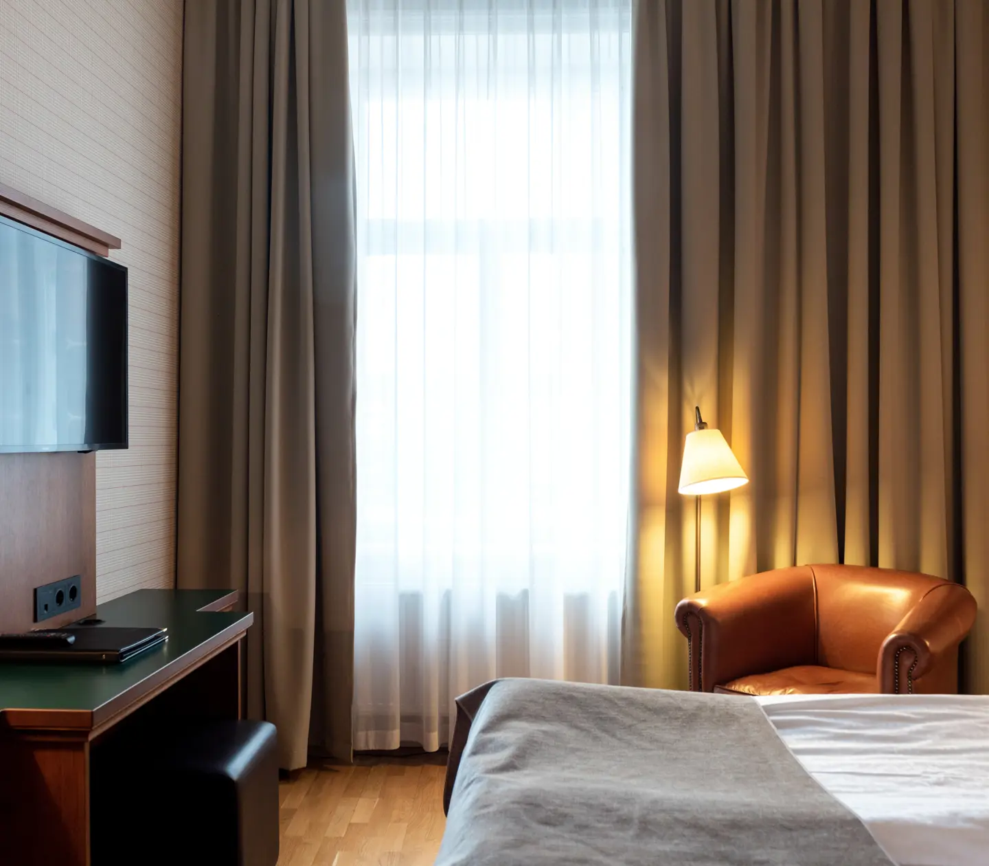 Hotellrum med säng, läderfåtölj och tv