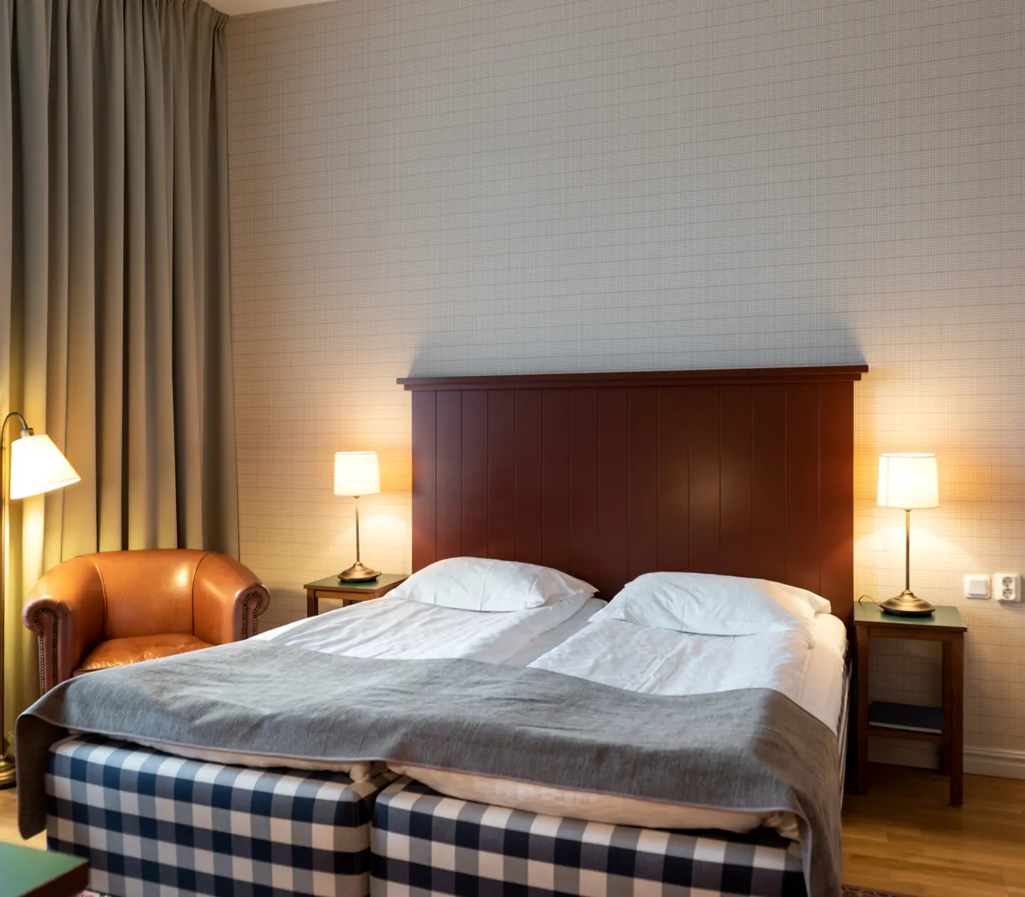 Hotellrum med Hästens-säng, läderfåtölj och sänglampor