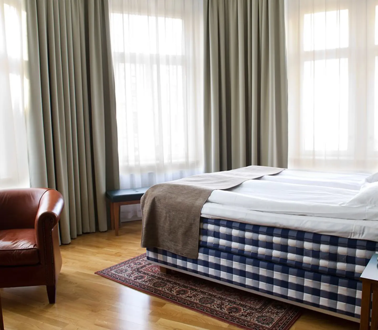 Hotellrum med Hästens-säng, läderfåtölj och fönster