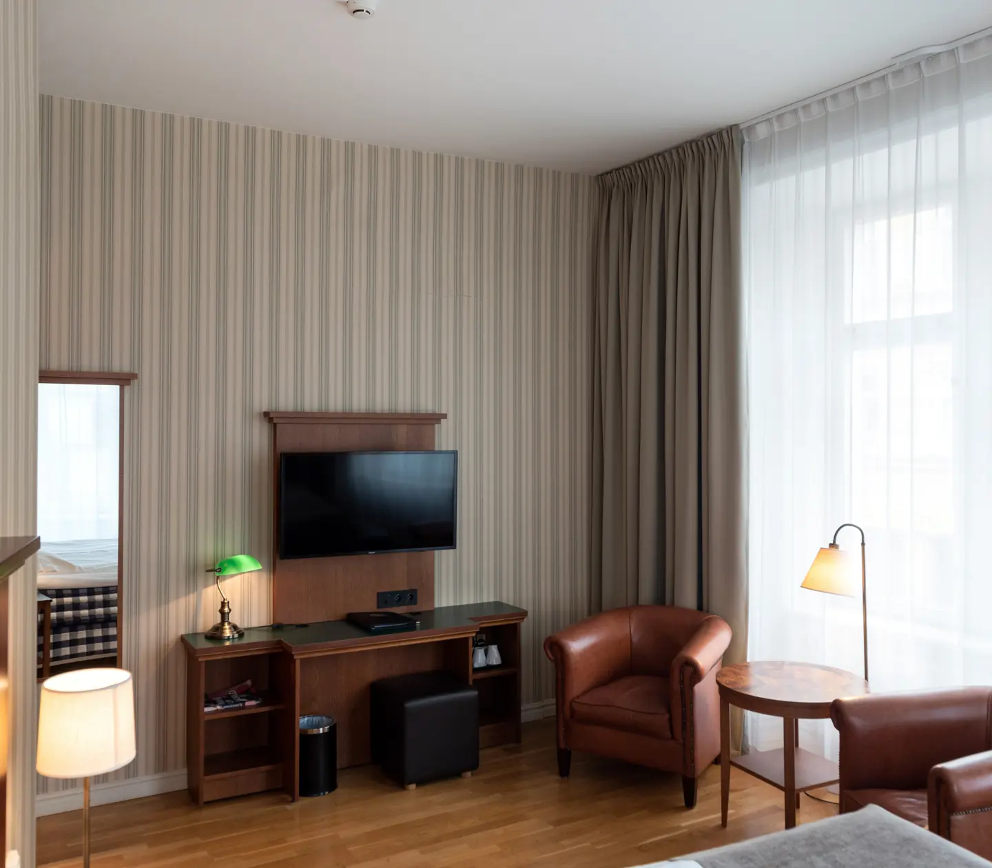 Hotellrum med skrivbord, läderfåtöljer och fönster