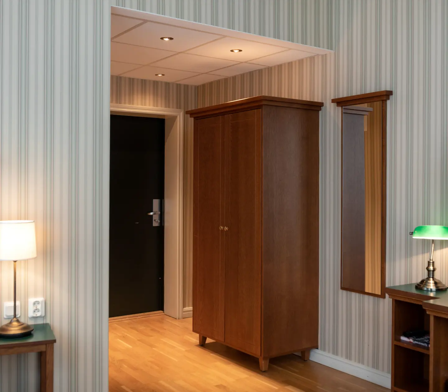 Hotellrum med garderob, spegel och tv