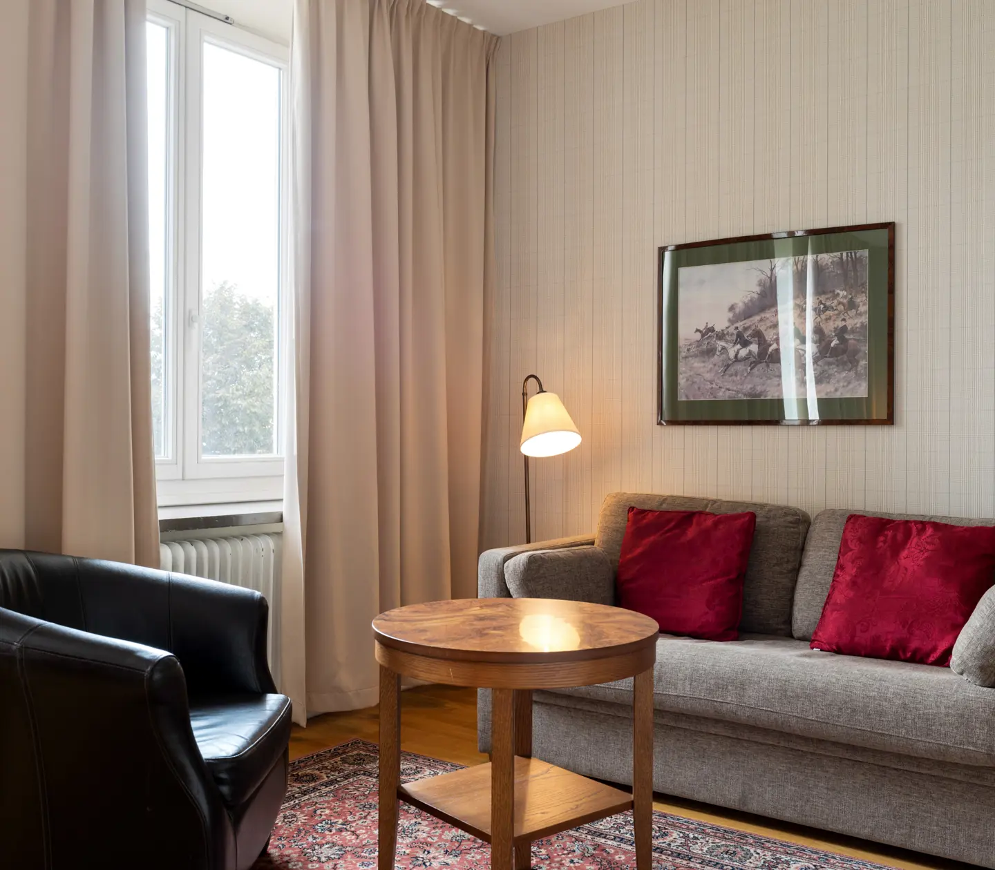 Hotellrum med soffgrupp, golvlampa och fönster