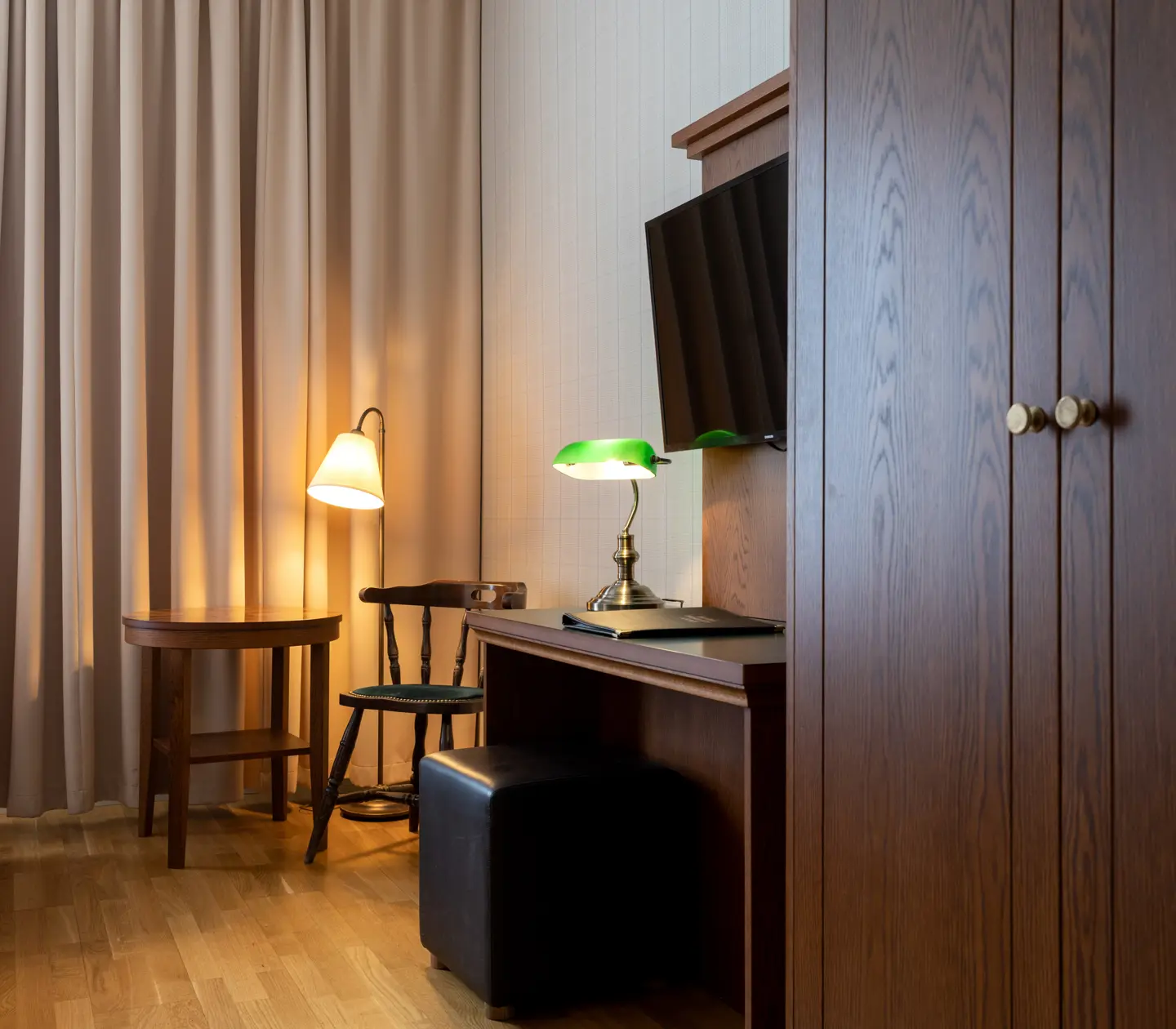 Mysigt hotellrum med gardin, skrivbord och garderob