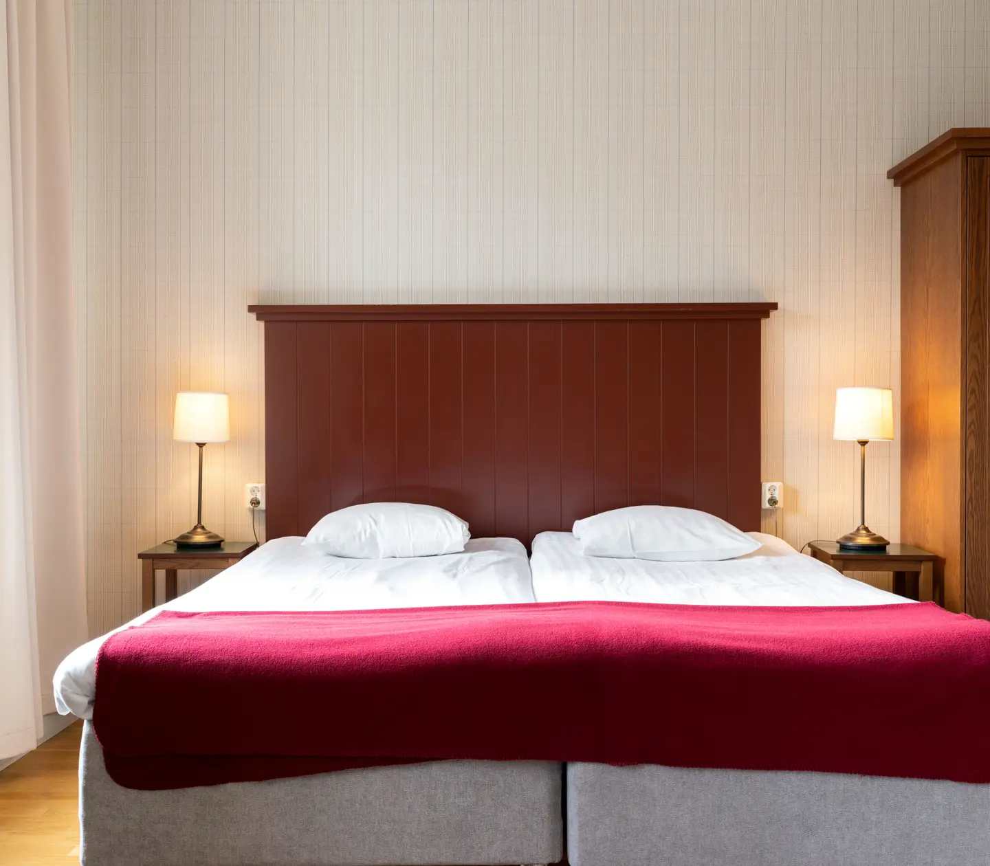 Mysigt hotellrum med säng, sänggavel i trä och sänglampor