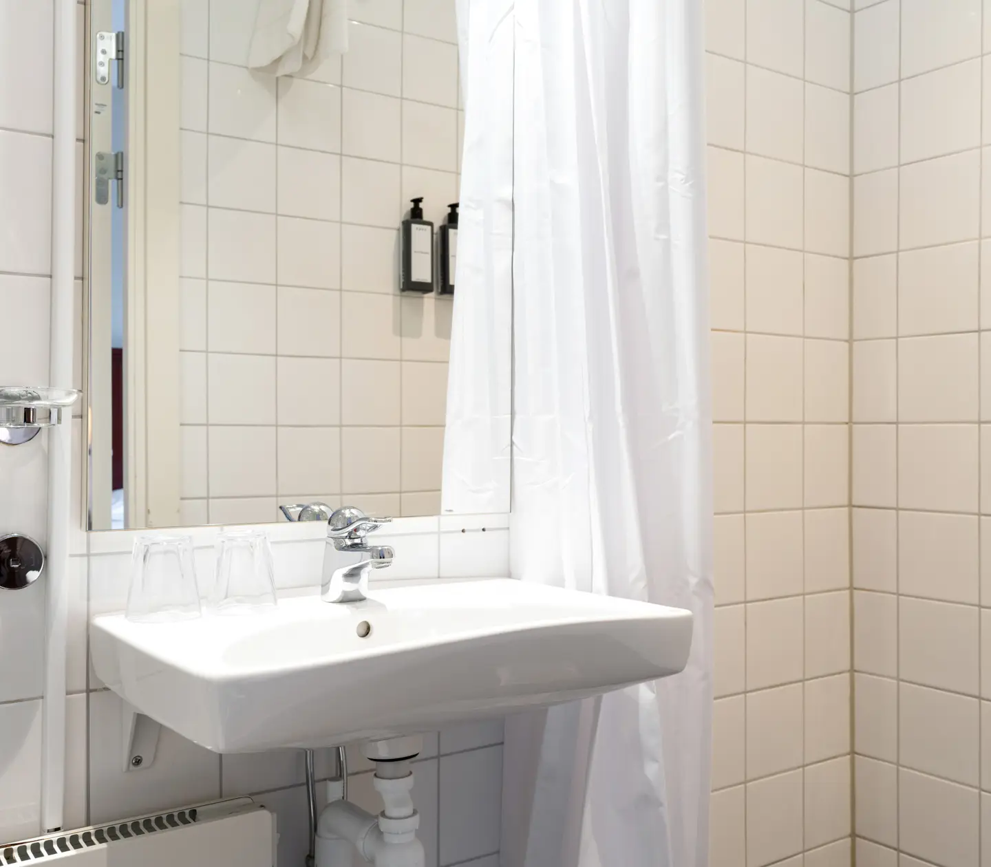Ljust badrum med duschdraperi, handfat och spegel