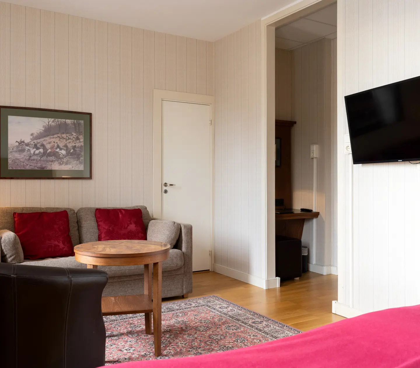 Mysigt hotellrum med soffa, tv och tavla