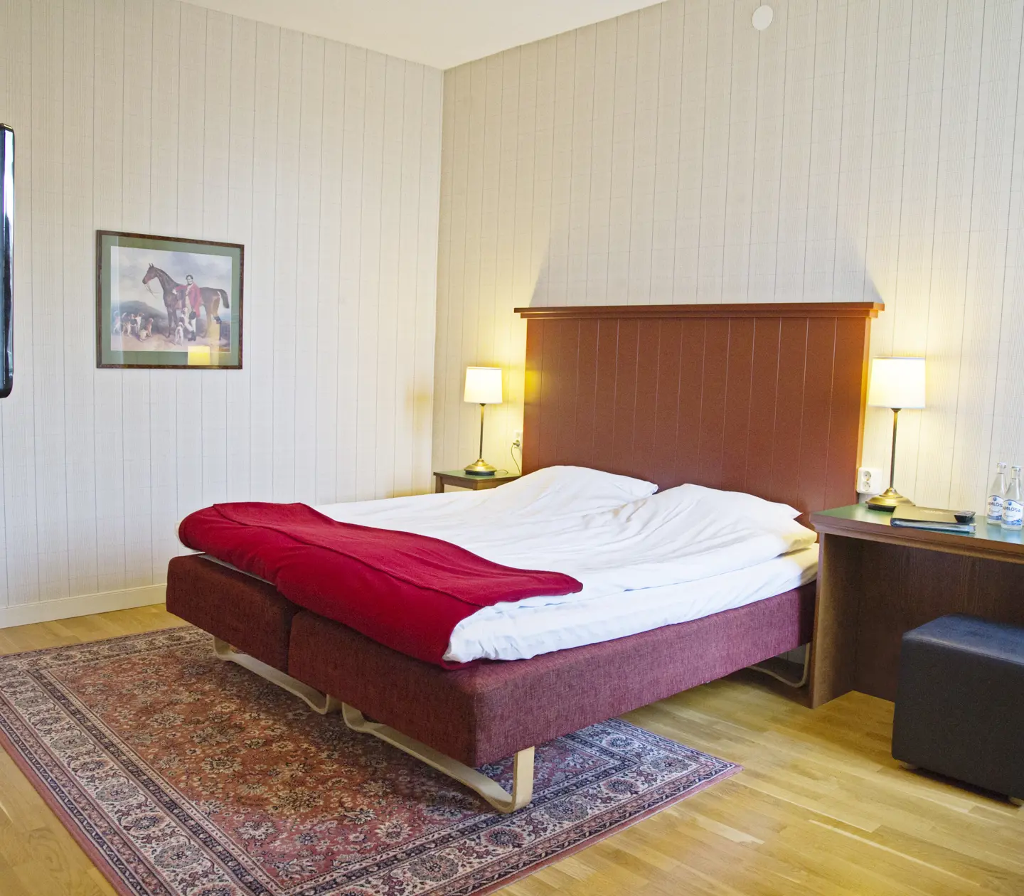 Mysigt hotellrum med säng, sänggavel i trä och skrivbord