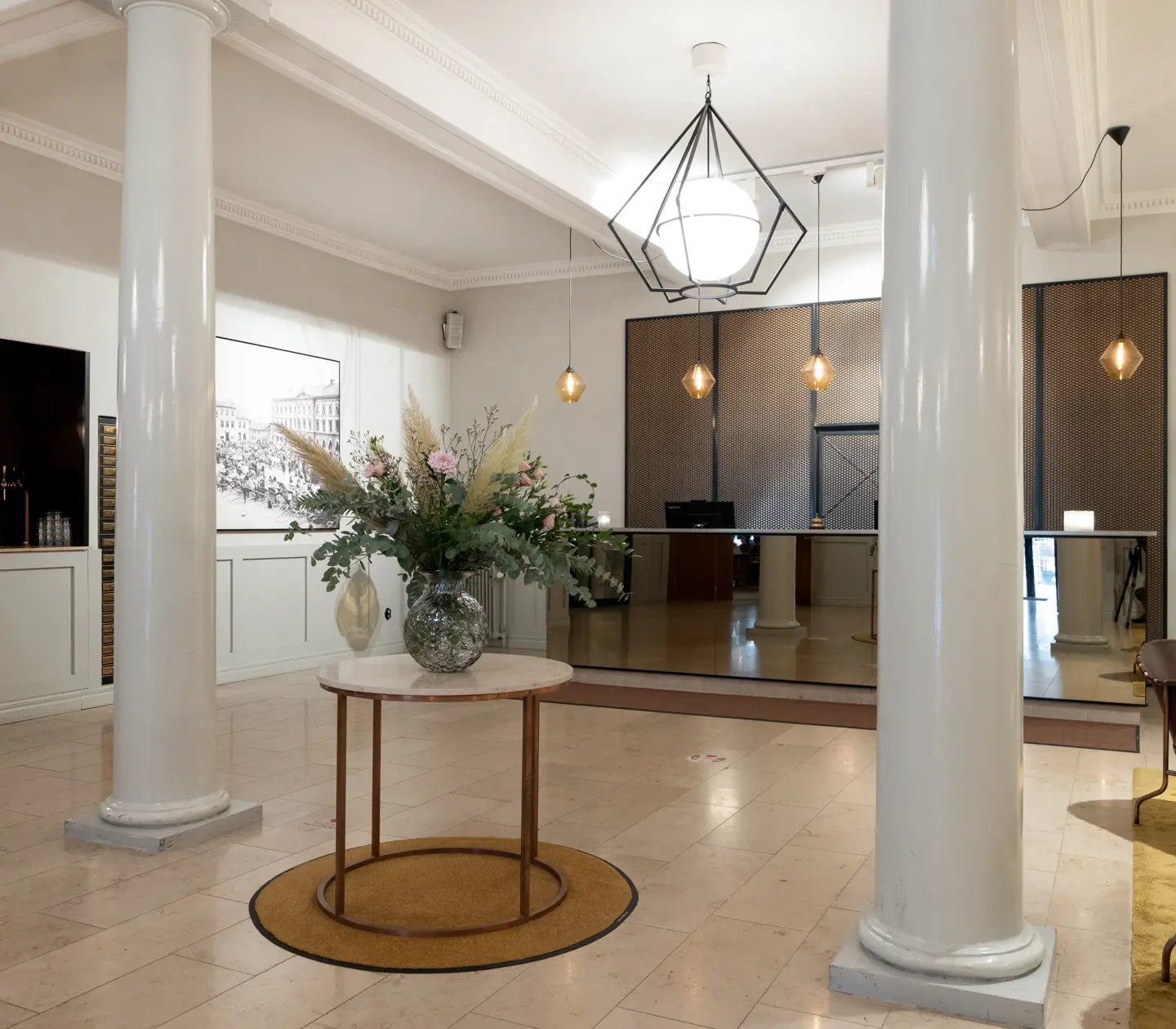 Hotellobby med stor blombukett, receptionsdisk och fåtöljer