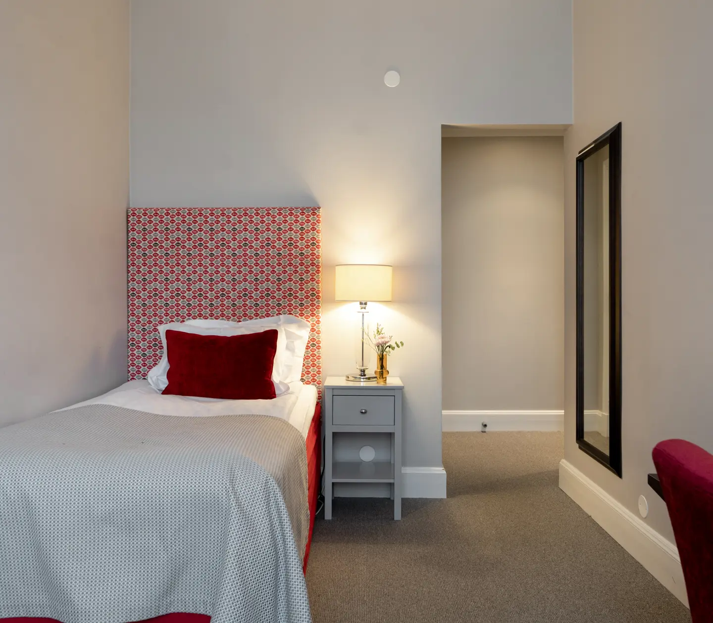 Mysigt hotellrum med enkelsäng, skrivbord, fåtölj och fönster