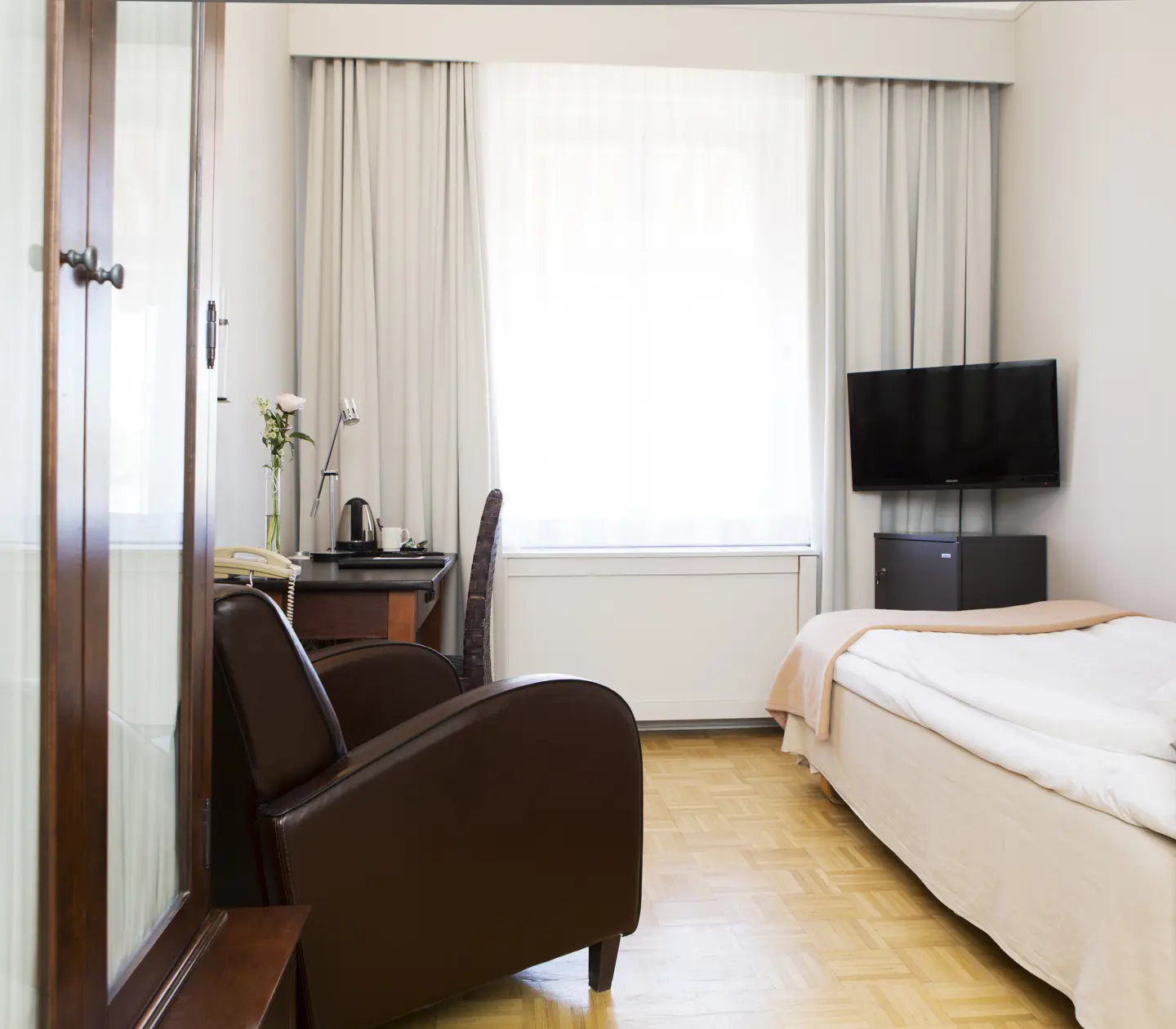 Mysigt hotellrum med enkelsäng med röd gavel, skrivbord och nattduksbord