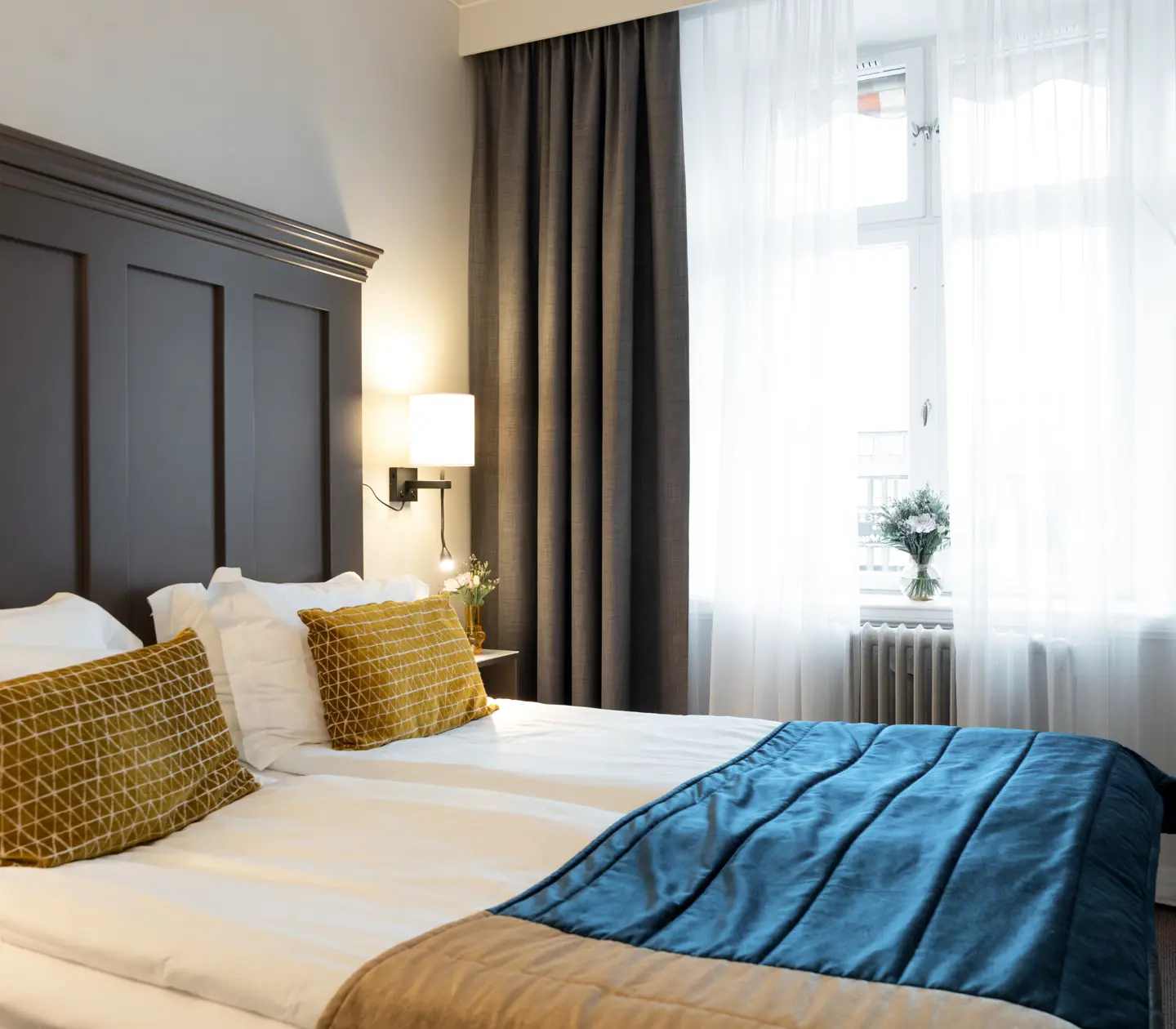 Mysigt hotellrum med del av dubbelsäng och stort fönster