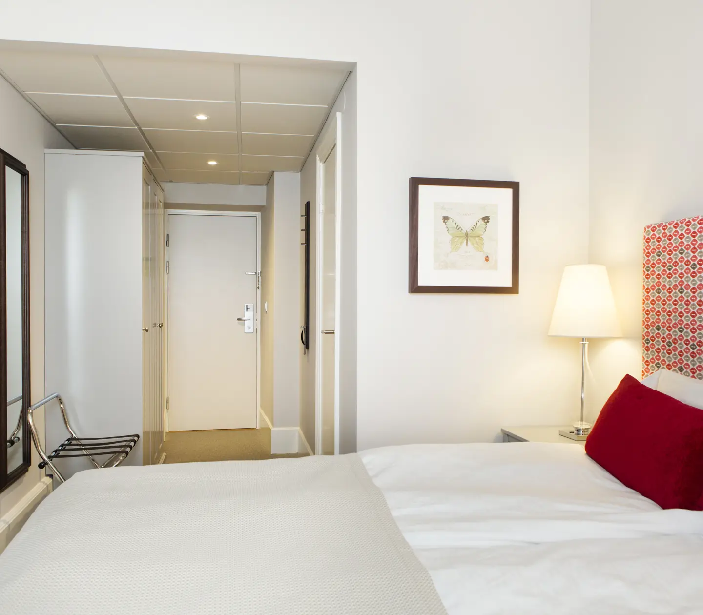 Hotellrum med dubbelsäng, spegel och tavla