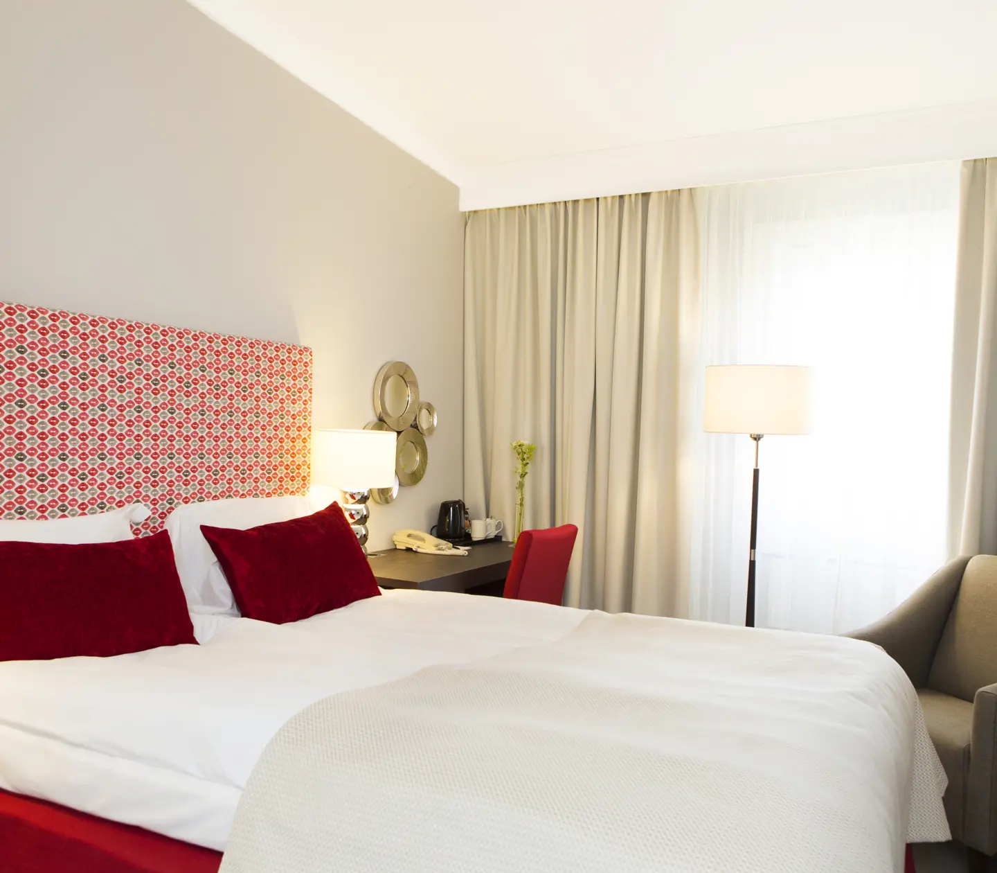 Hotellrum med dubbelsäng, skrivbord och fåtölj